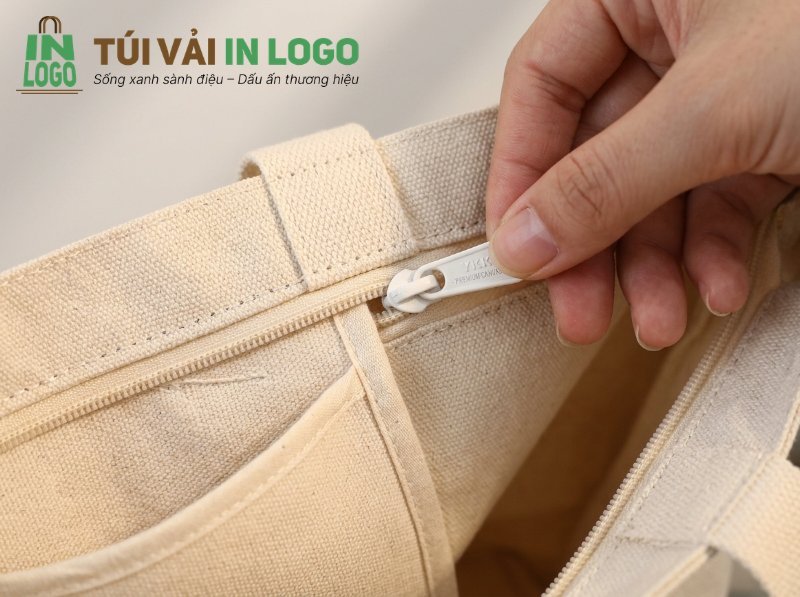 Chi tiết dây kéo YKK chất lượng cao trên túi vải in logo màu kem, cho thấy tiêu chí độ bền và sự tỉ mỉ trong sản phẩm quà tặng doanh nghiệp.